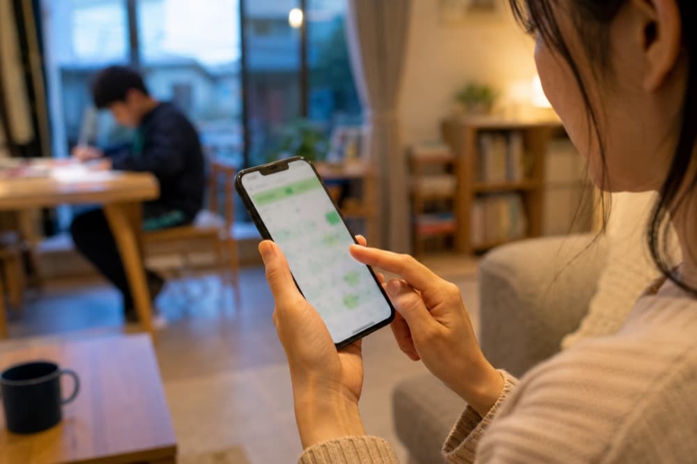 リビングでスマートフォンから面談を予約する保護者の手元の写真