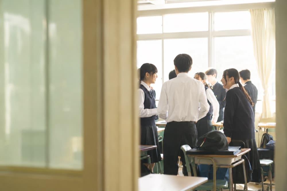 休み時間の教室で談笑する生徒たちの写真